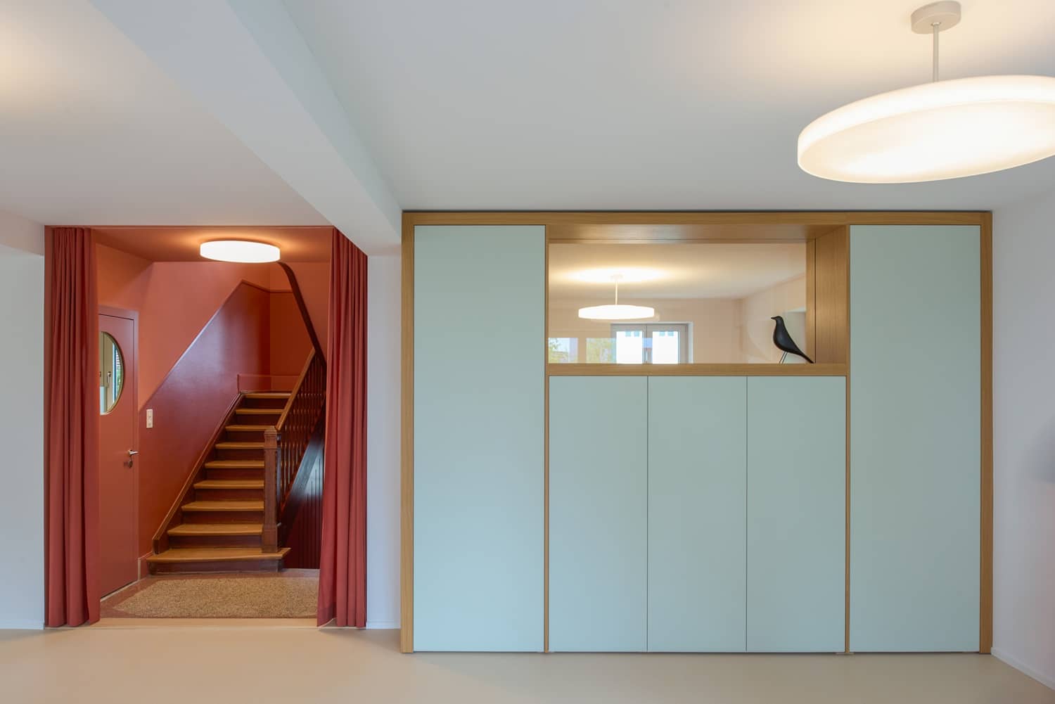Neben einem grossen Wandschrank ist ein Durchgang, der in ein rotes Treppenhaus f&uuml;hrt